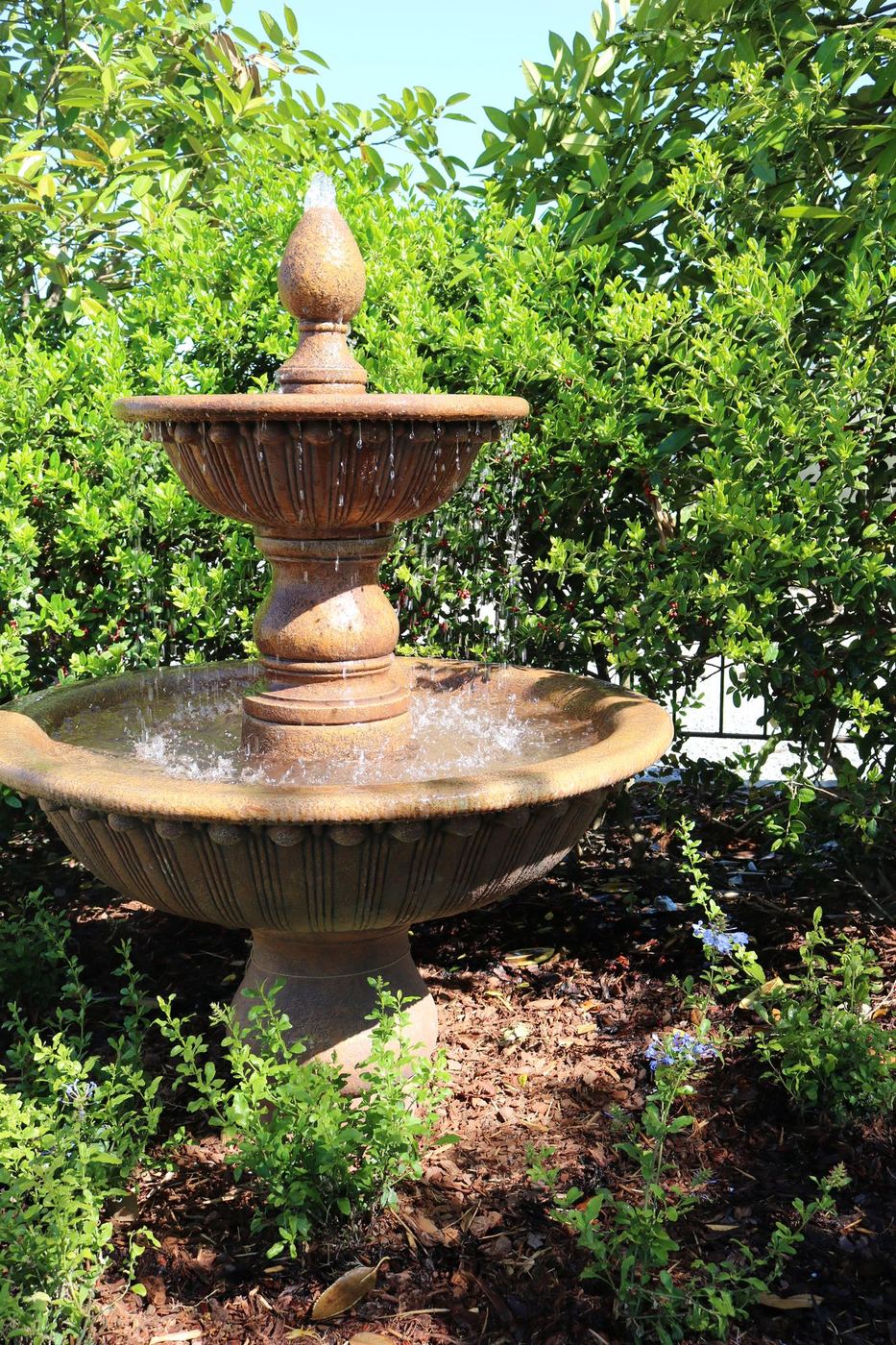 Two-tier cast-stone fountain surrounded by garden planting